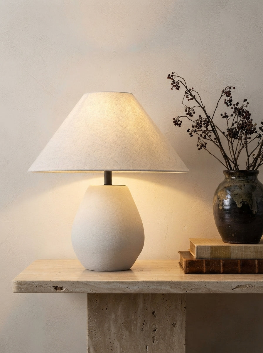 Lampe à poser en céramique blanche sur une console en travertin